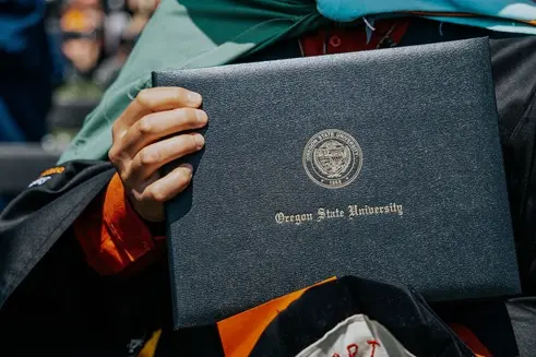 This is an image of an Oregon State graduate holding a diploma